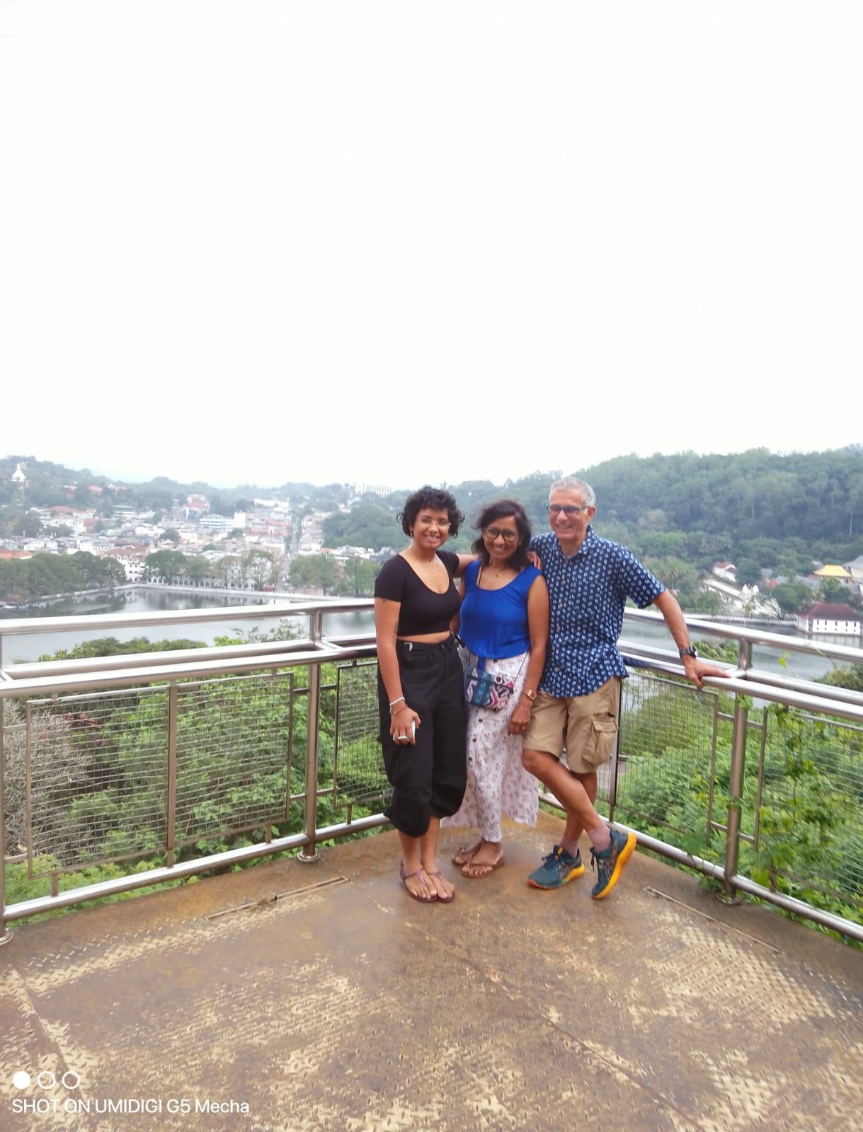 Three guests at a viewpoint above a hill-country town