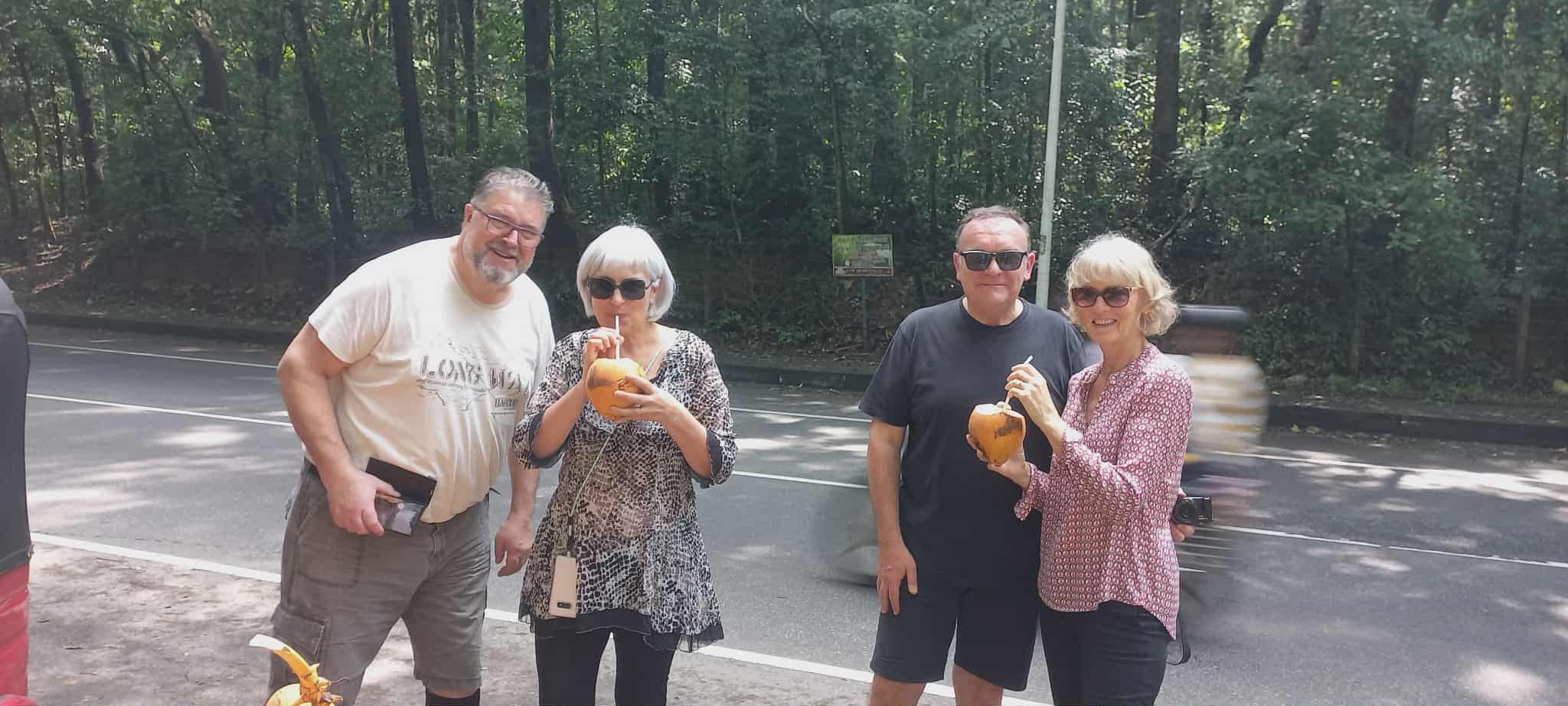 Two couples with king coconuts at the roadside