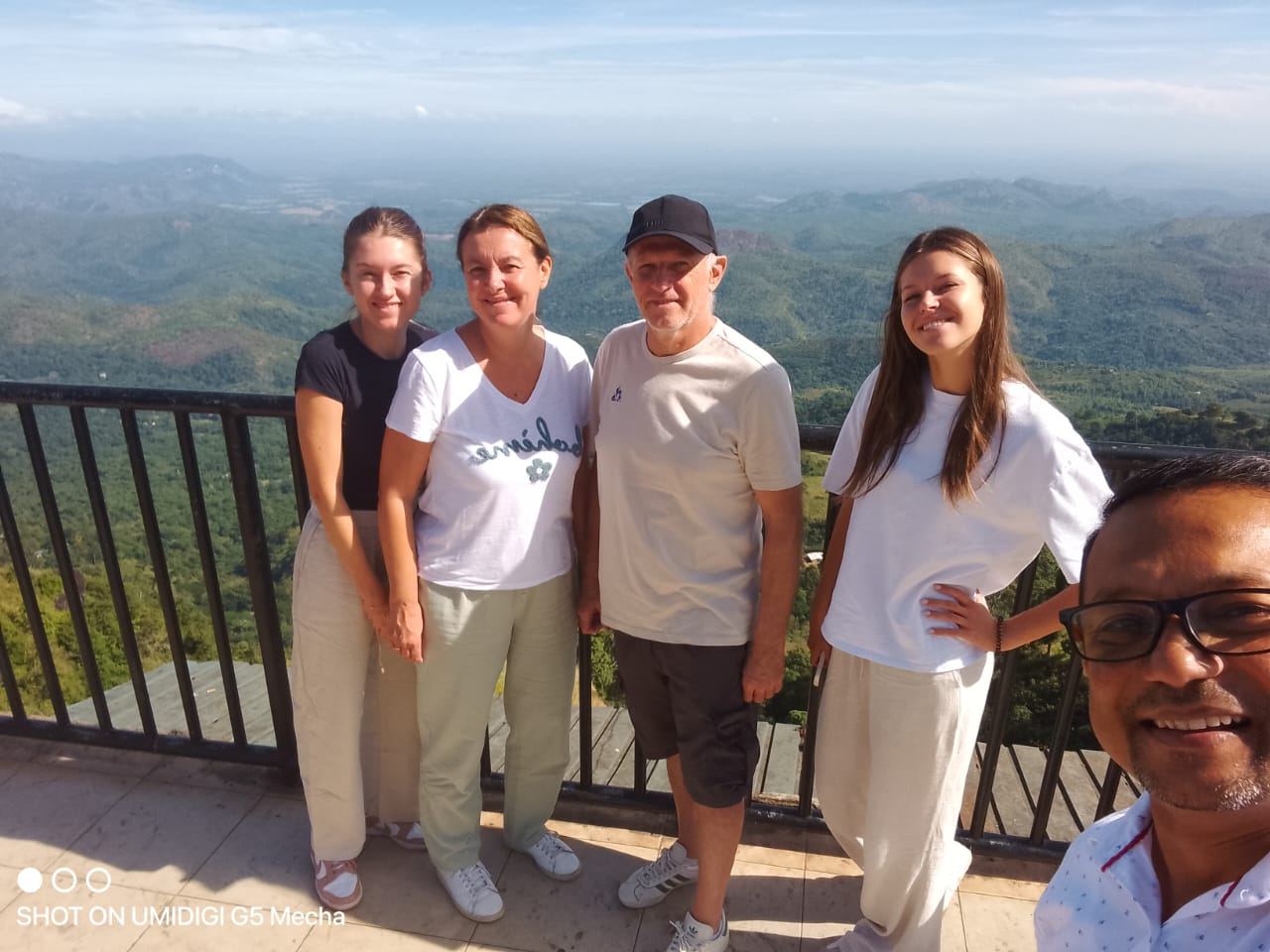 A family at a hill-country viewpoint with their guide taking a selfie