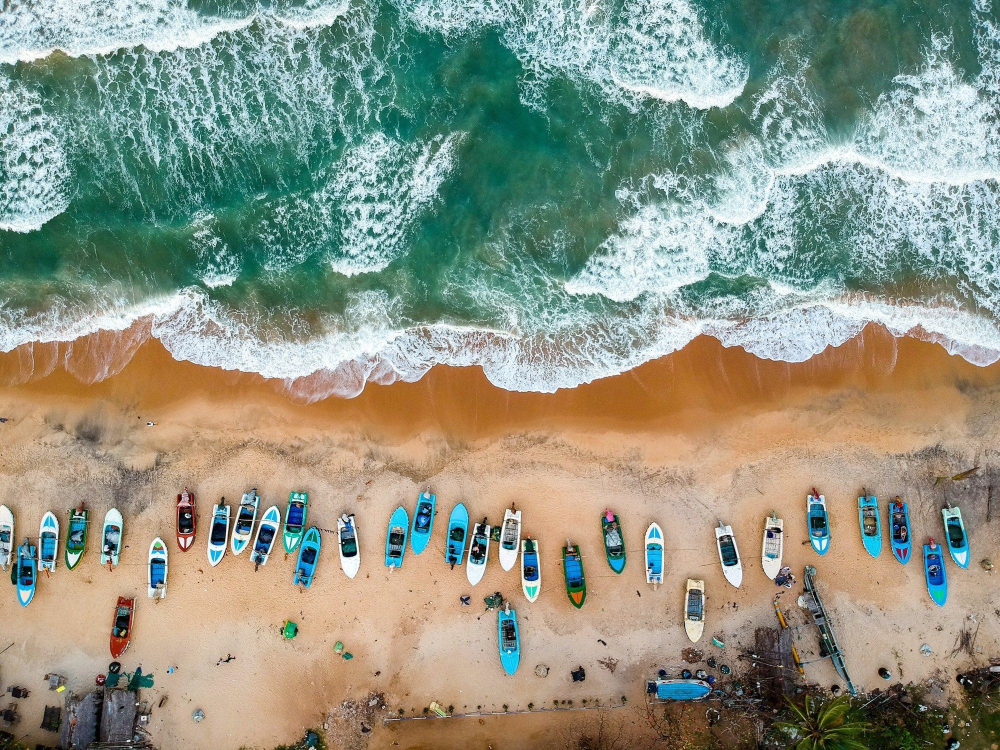 Aerial view of Arugam Bay, with fishing boats on the sand and surf breaking offshore