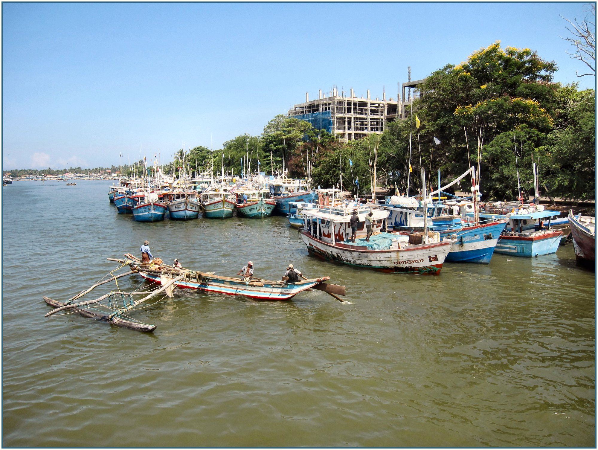 An outrigger canoe and colourful fishing boats on the Negombo lagoon