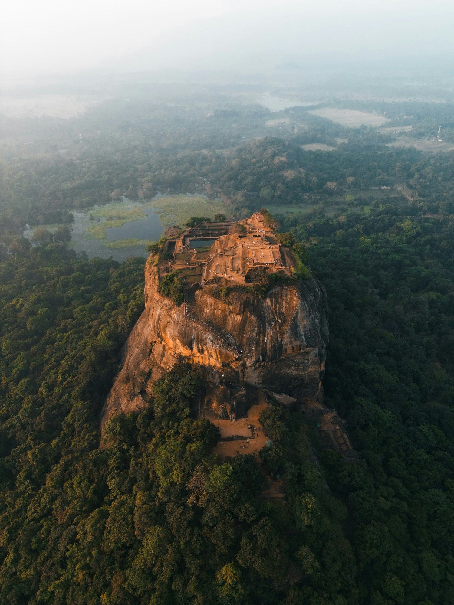 Sigiriya rock rising from the forest in the morning mist