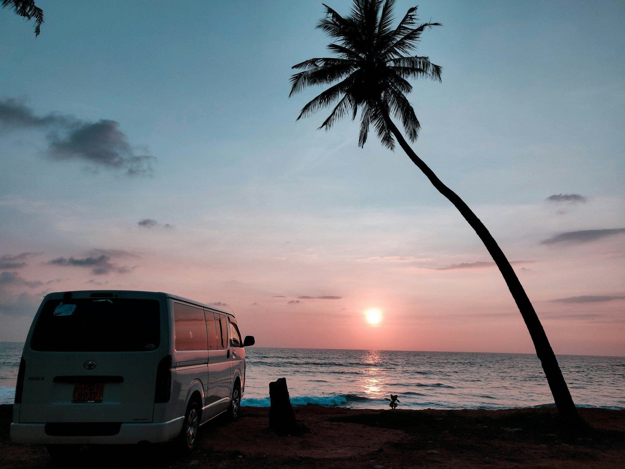 A Toyota HiAce van parked by the sea at sunset in Hikkaduwa
